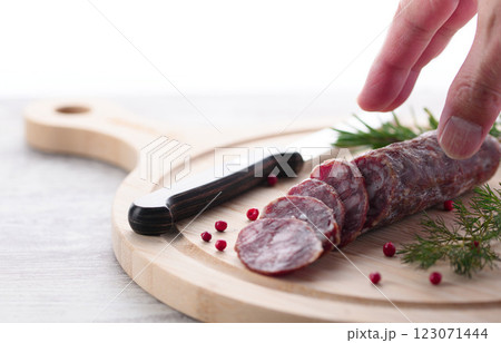 カッティングボードの上にのせた熟成サラミ ピンクペッパーとローズマリー カッティングボードの上にのせた熟成サラミ ピンクペッパーとローズマリー 123071444