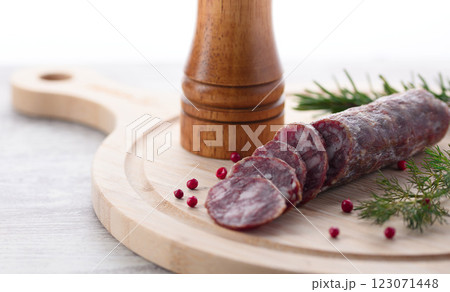 カッティングボードの上にのせた熟成サラミ　ピンクペッパーとローズマリー 123071448
