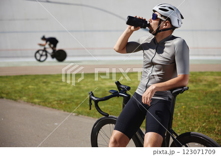 Sportsman taking break drinking water during cycling workout on track Sportsman taking break drinking water during cycling workout on track 123071709