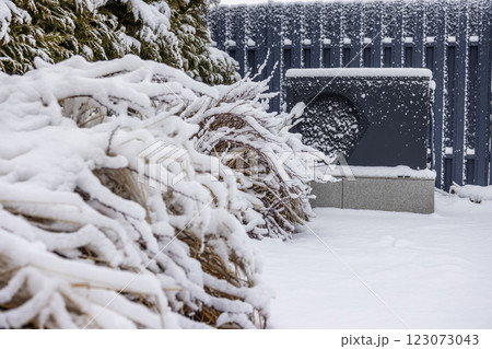 Outdoor heat pump unit covered in snow, providing energy-efficient heating for a swimming pool in winter. 123073043
