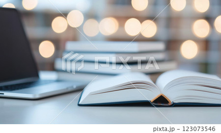 Open book on desk with laptop and blurred lights in background 123073546