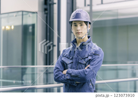 ヘルメットを被って腕組みをして立つ建設現場の若い男性作業員　撮影協力:スカパー東京メディアセンター 123073910