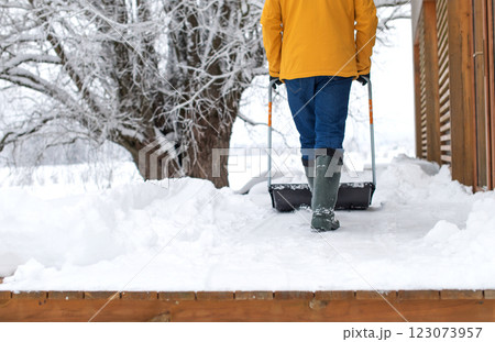 Rear view on man with snow shovel cleaning snow on terrace of the house 123073957
