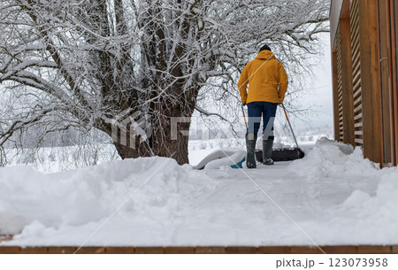 Rear view on man with snow shovel cleaning snow on terrace of the house Rear view on man with snow shovel cleaning snow on terrace of the house 123073958