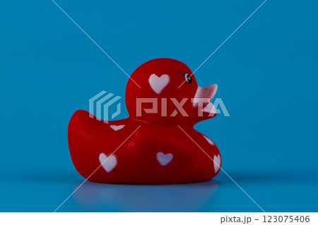 Charming Red Rubber Duck with Heart Patterns Against a Bright Blue Background Creating a Fun Contrasting Visual Appeal Charming Red Rubber Duck with Heart Patterns Against a Bright Blue Background Creating a Fun Contrasting Visual Appeal 123075406