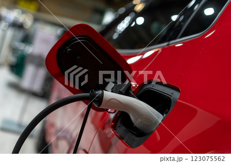 Closeup of power supply plugged into an modern electric car. Electric or EV car charging station. Closeup of power supply plugged into an modern electric car. Electric or EV car charging station. 123075562
