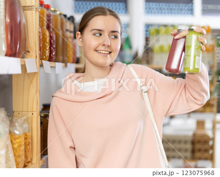 Female shopper chooses bottle of smoothie while shopping in supermarket Female shopper chooses bottle of smoothie while shopping in supermarket 123075968