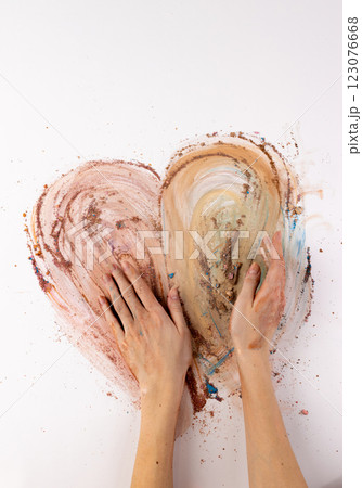 An Artistic Expression of Love: Two Hands Creating a Heart Shape with Earthy Pigments on a White Canvas 123076668