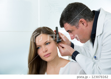 Doctor ENT checking ear with otoscope to woman patient 123078162