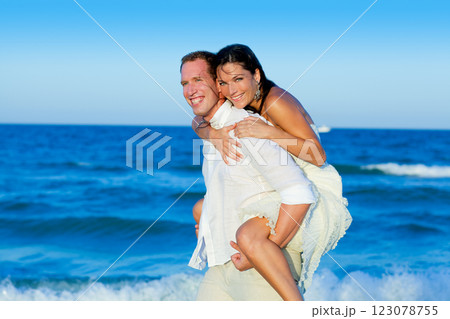 couple in love piggyback playing in beach 123078755