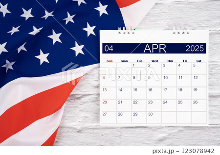 April 2025 Monthly desk calendar and United States of America flag. April 2025 Monthly desk calendar and United States of America flag. 123078942