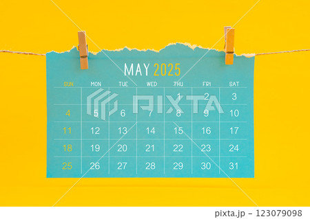 May 2025 calendar tearing hanged with brown rope on yellow background. May 2025 calendar tearing hanged with brown rope on yellow background. 123079098