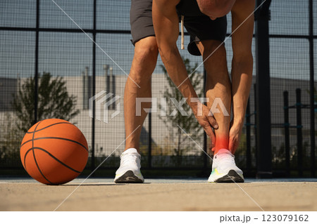 Basketball ankle injury or pain. Basketball player check legs after workout of sport stadium. Professional athlete or sportsman with accident. Man check pain in leg after sport workout. 123079162