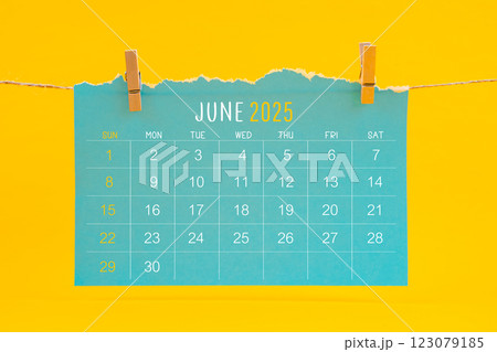 June 2025 calendar tearing hanged with brown rope on yellow background. 123079185
