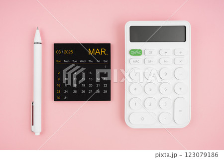 March 2025 calendar and white calculator with pen on pink background. 123079186