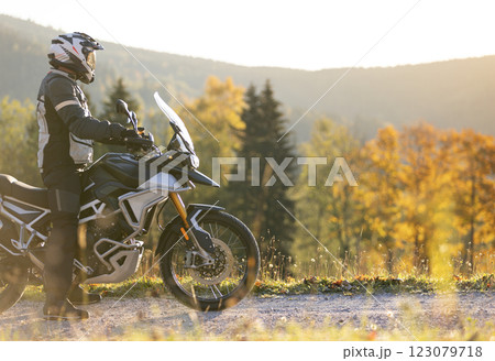 Driver posing on motorcycle during sunrise, rural countryside 123079718