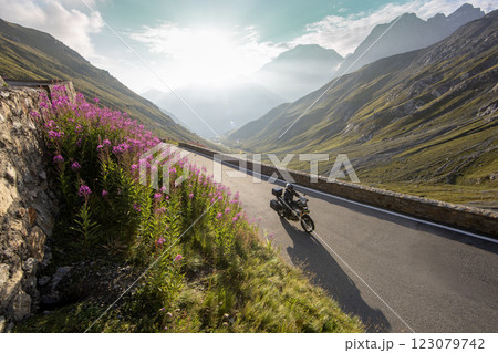 Motorbiker riding in Italian Alps during sunrise, dramatic sky. Travel and freedom, outdoor activities 123079742