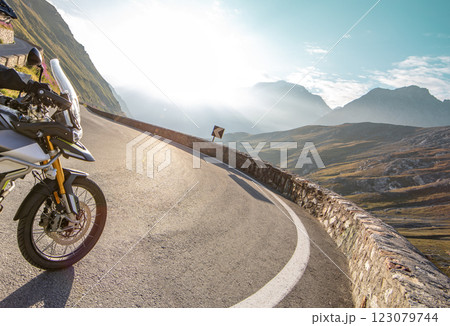 Motorbiker riding in Italian Alps during sunrise, dramatic sky. Travel and freedom, outdoor activities 123079744