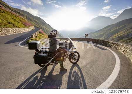 Motorbiker riding in Italian Alps during sunrise, dramatic sky. Travel and freedom, outdoor activities 123079748