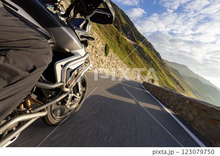 Motorbiker riding in Italian Alps during sunrise, dramatic sky. Travel and freedom, outdoor activities 123079750