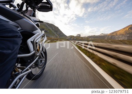 Motorbiker riding in Italian Alps during sunrise, dramatic sky. Travel and freedom, outdoor activities Motorbiker riding in Italian Alps during sunrise, dramatic sky. Travel and freedom, outdoor activities 123079751