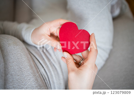 Pregnant woman holding red heart symbolizing love and connection 123079809