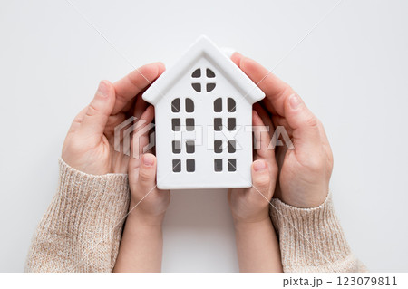 Caucasian hands holding ceramic house model representing home safety and security 123079811