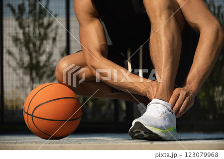Basketball ankle injury or pain. Basketball player check legs after workout of sport stadium. Professional athlete or sportsman with accident. Man check pain in leg after sport workout. Close up. 123079968