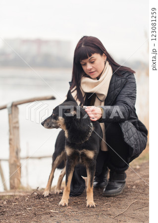A woman plays with her dog on a walk near a lake A woman plays with her dog on a walk near a lake 123081259