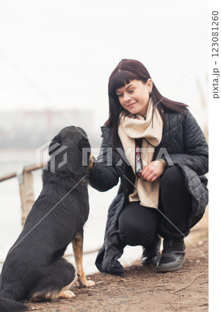 A woman plays with her dog on a walk near a lake A woman plays with her dog on a walk near a lake 123081260