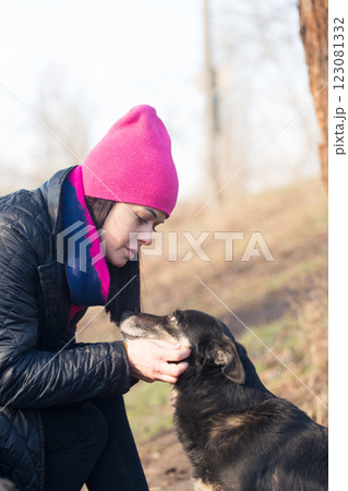 Woman in a hat hugging her dog on a walk on a sunny day 123081332