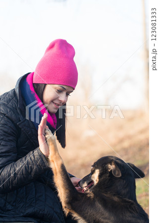 Woman in hat in park teaches dog to give high five, close-up 123081333