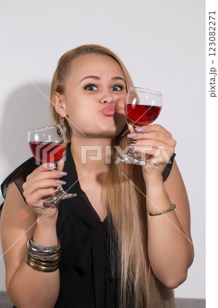 A woman is holding two wine glasses and making a funny face 123082271