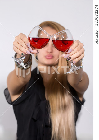 A woman is holding two wine glasses and making a face 123082274