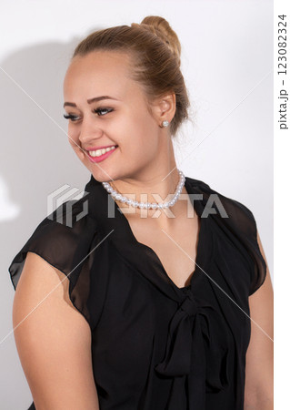 A woman wearing a black dress and a pearl necklace 123082324