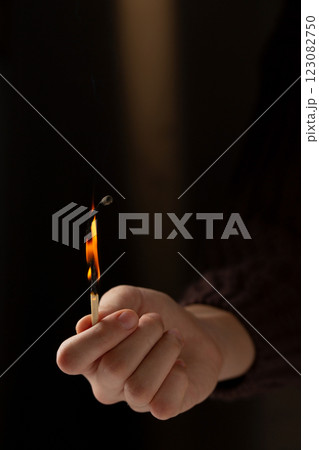 Hand holding a lit match. Concept of warmth and comfort as a person holds a match to light a candle or fire 123082750