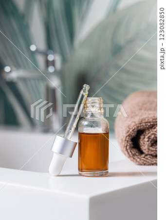 Pipette set on opened clear glass dropper bottle near dark grey bath towel closeup, cosmetic mockup Pipette set on opened clear glass dropper bottle near dark grey bath towel closeup, cosmetic mockup 123082850