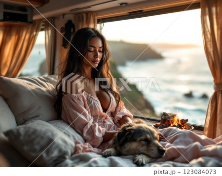 Woman relaxing in camper van with dog by the sea at sunset 123084073