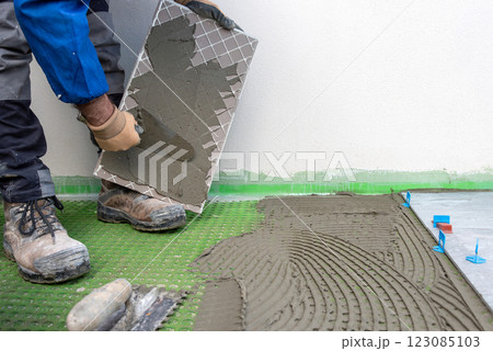 Tiler at work installing new floor with tiles. Construction. Tiler at work installing new floor with tiles. Construction. 123085103