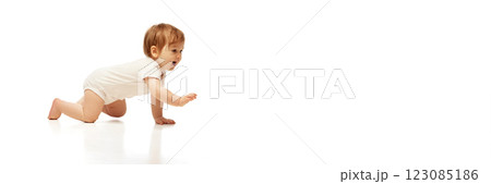 Banner. Baby in onesie crawling forward with joyful expression and arm extended against white background with negative space. 123085186