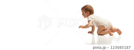 Banner. Baby wearing in white onesie, crawling forward while focused on destination against white background with negative space. 123085187