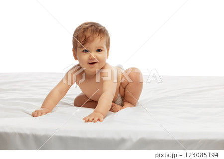 Little baby crawling on soft white bed while looking ahead with curiosity and excitement against white background. 123085194