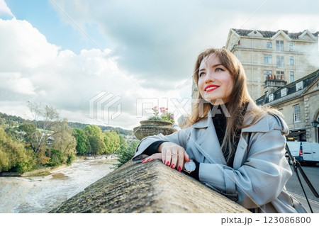 Portrait of Young Woman enjoying sunny day and view of bay with river in picturesque location of Bath city, England. Holiday, travel walk in old European city. Local travel, Sightseeing trip concept. 123086800
