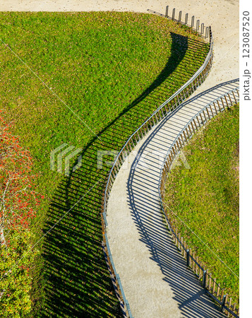Winding gravel path with metal railings, view from above, interesting shadow lines on gravel path Winding gravel path with metal railings, view from above, interesting shadow lines on gravel path 123087520