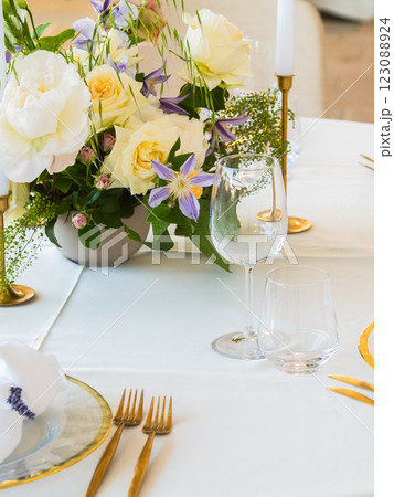 Wedding banquet concept. Chairs and round table for guests, served with cutler and, flowers and crockery and covered with a tablecloth 123088924