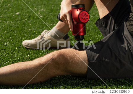 Man massaging legs with massage percussion gun after training. Applying therapeutic percussion massager gun. Man massaging legs with massage percussion gun after training. Applying therapeutic percussion massager gun. 123088969