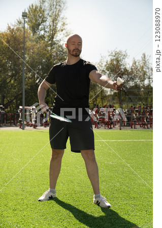 Man teach playing badminton on floor sport court in sunny shadow. Outdoors. Close up. Vertical format. 123088970
