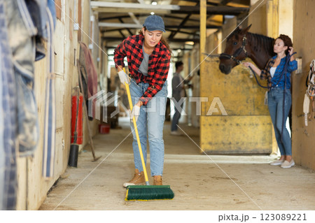 Girl cleans the floor of a stable with fetlock Girl cleans the floor of a stable with fetlock 123089221