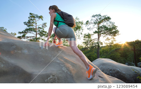 Young woman climbing alone on rocky mountain path. Female hiker enjoying difficult challenge on wilderness trail. Active way of life concept Young woman climbing alone on rocky mountain path. Female hiker enjoying difficult challenge on wilderness trail. Active way of life concept 123089454