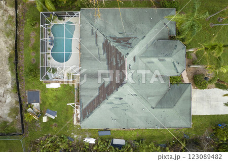 Wind damaged house roof with missing asphalt shingles after hurricane Ian in Florida. Repair of home rooftop concept 123089482